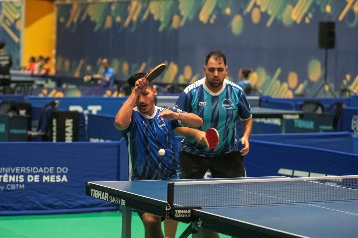 Jonathan ataca de forehand em jogo de duplas numa competição da CBTM